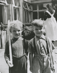 876987 Afbeelding van twee jongetjes die zich presenteren als soldaat op de binnenplaats van het opvanghuis ...